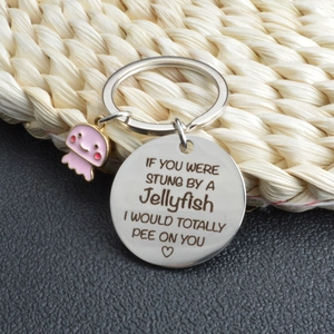 Close-up of stainless steel keychain featuring a pink enamel jellyfish charm and engraved metal tag