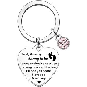 Macro shot of stainless steel heart keychain with pink rhinestone and baby feet engraving