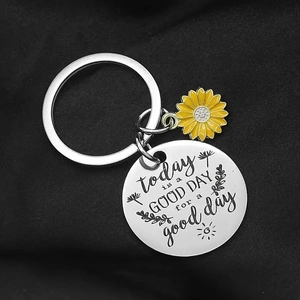Macro shot of stainless steel keychain with sunflower charm and engraved quote on black background