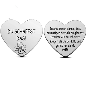 Macro shot of silver heart tokens featuring Du Schaffst Das engraving and clover icon