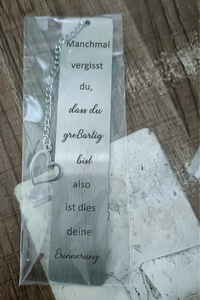 Detail of brushed stainless steel bookmark with engraved text and heart charm in packaging