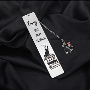 Detail of stainless steel cat bookmark with tassel on black silk background