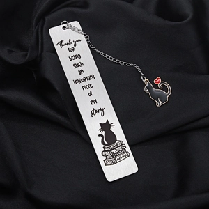 Close-up of stainless steel bookmark with engraved cat design on black silk fabric