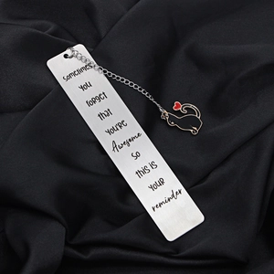 Detailed close-up of a brushed stainless steel cat bookmark on black silk fabric
