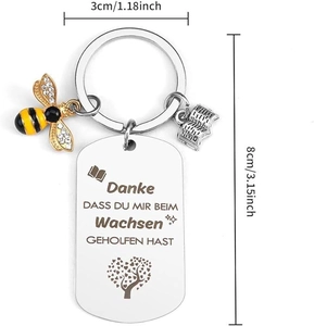 Macro detail of engraved stainless steel keychain with bee charm and teacher gift motifs