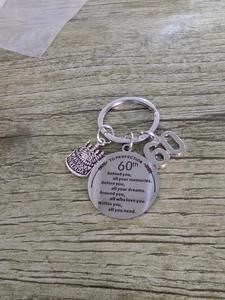 Detail of 60th birthday stainless steel keychain with cake charm and engraved poem