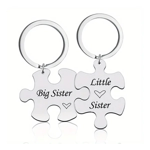 Macro shot of puzzle-shaped stainless steel keychains with Little and Big Sister engraving