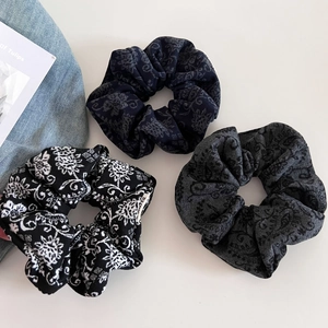 Close-up of three vintage paisley wool hair scrunchies in navy, black and grey