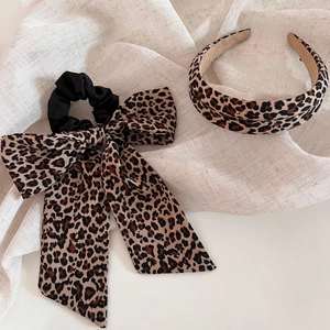 Chic leopard print headband and large bow scrunchie set displayed on linen fabric