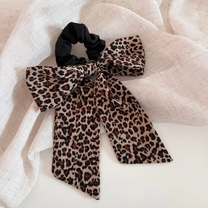 Vintage leopard print bow scrunchie on linen background for elegant hair styling