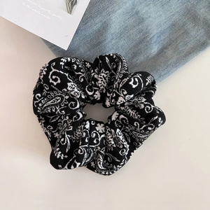 Detail shot of vintage black and white paisley pattern scrunchie on fabric backdrop