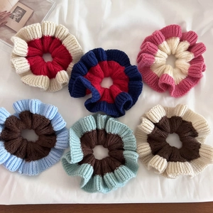 Set of 6 knitted patchwork scrunchies in various winter colors on a soft white cloth
