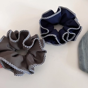 Vue détaillée des chouchous en tissu bleu marine et marron avec bord à carreaux