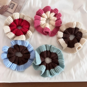 Flat lay of five knitted ruffled hair scrunchies in various two-tone color combinations