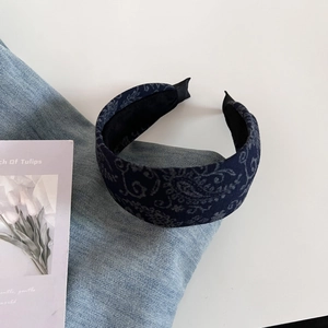 Close-up of retro navy blue paisley pattern headband on casual denim background