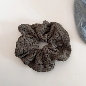 Close-up of a dark taupe knit scrunchie with detailed crochet hollow texture and ruffles