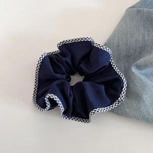 Gros plan détaillé du chouchou en tissu bleu foncé avec bordure à carreaux noirs et blancs