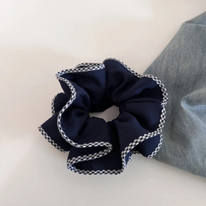 Chouchou bleu marine avec bordure à carreaux sur un fond clair et minimaliste
