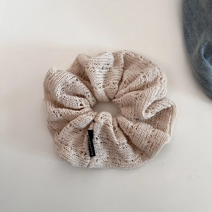 Close-up of beige hollow knit scrunchie featuring Blind For Love woven black label