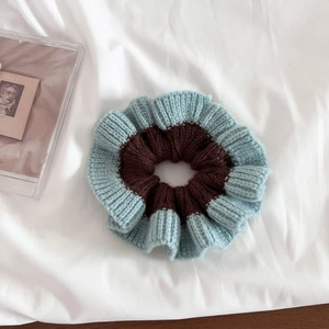 Detailed view of the dual-color knitted scrunchie with light blue and brown wavy edges