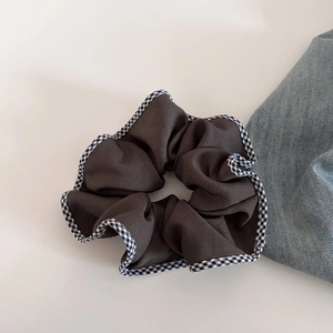 Détail d'un chouchou en tissu marron café avec bordure à carreaux noirs et blancs