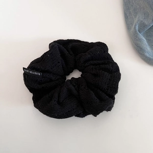 Detail of black hollow crochet scrunchie with Blind For Love text tag and knit texture