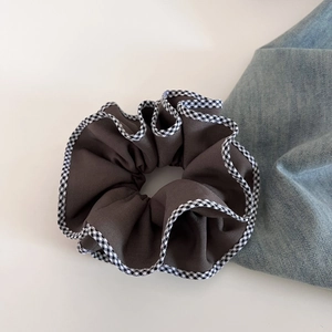 Gros plan d'un chouchou marron avec bordure à carreaux noir et blanc sur denim