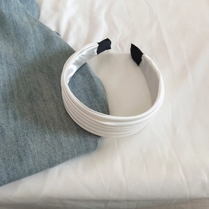 Gros plan d'un serre-tête en satin blanc plissé avec des couches texturées élégantes