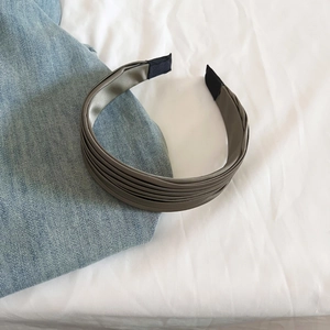 Détail d'un serre-tête élégant en satin plissé vert olive avec embouts noirs confortables