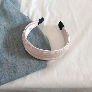Détail d'un serre-tête en satin plissé rose pâle avec texture élégante pliée