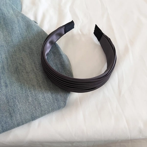 Détail du serre-tête en satin plissé gris anthracite avec une texture élégante du tissu
