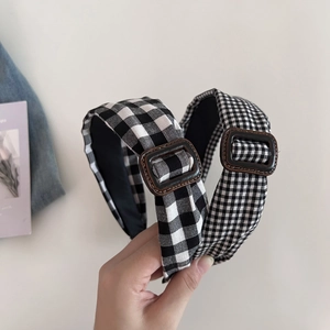 Close-up of black and white gingham headband with a brown resin buckle detail