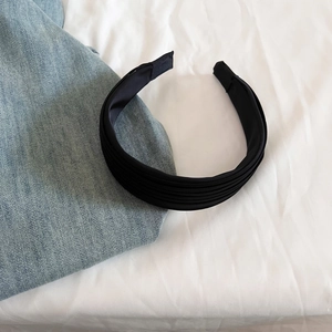 Détail d'un serre-tête plissé en satin noir élégant avec une texture de tissu brillant