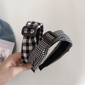 Close-up of black and white gingham headbands with decorative brown square buckles