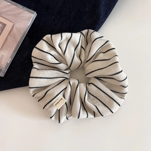 Détail d'un chouchou en maille rayée avec une étiquette faite main sur le tissu