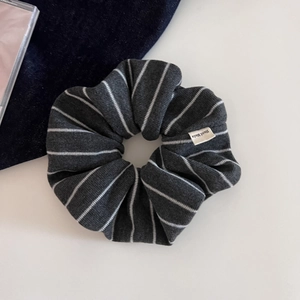 Détail d'un chouchou en tricot rayé gris avec une étiquette en tissu Hand Made