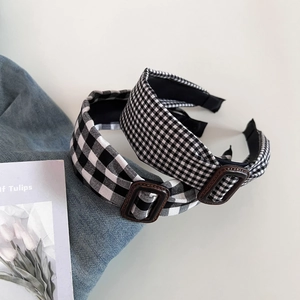 Close-up of black and white checkered headband with vintage leather buckle detail
