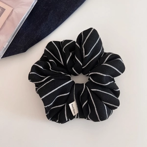 Détail d'un chouchou en maille rayé noir et blanc avec une étiquette tissée Hand Made chic