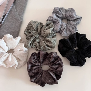 Detailed texture of five colorful velvet scrunchies with soft crushed velvet material