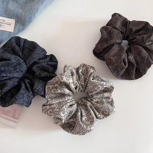 Detailed macro view of three vintage paisley pattern scrunchies on white background