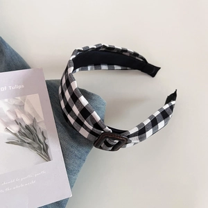 Close-up of black and white gingham headband with vintage brown leather buckle detail