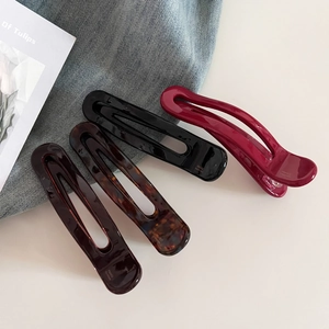 Detail view of four colorful handmade acetate hair clips on a soft denim background