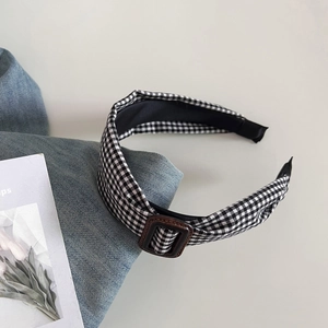 Close-up of black and white checkered headband with vintage brown buckle detail