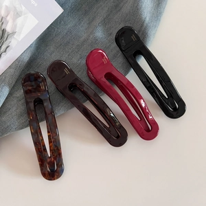 Detailed macro view of four glossy acetate hair clips in tortoiseshell and rich solid colors