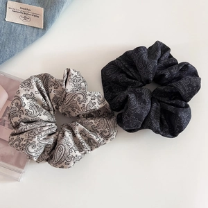 Close-up of paisley print scrunchies in grey and black cotton fabric texture