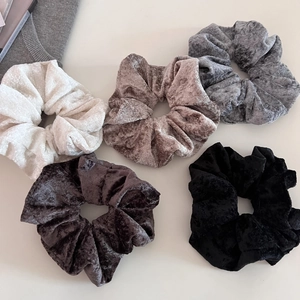 Close-up of five neutral velvet hair scrunchies with soft pleated texture and high elasticity