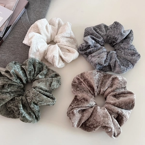 Close-up of four soft velvet scrunchies in white, grey, green, and coffee brown colors