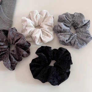 Macro shot of four velvet scrunchies in cream, grey, brown and black colors