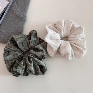 Detail of plush velvet scrunchies in cream and olive green with soft pleated texture