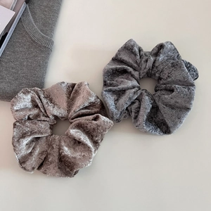 Close-up of soft velvet scrunchies in champagne taupe and dark grey with rich texture